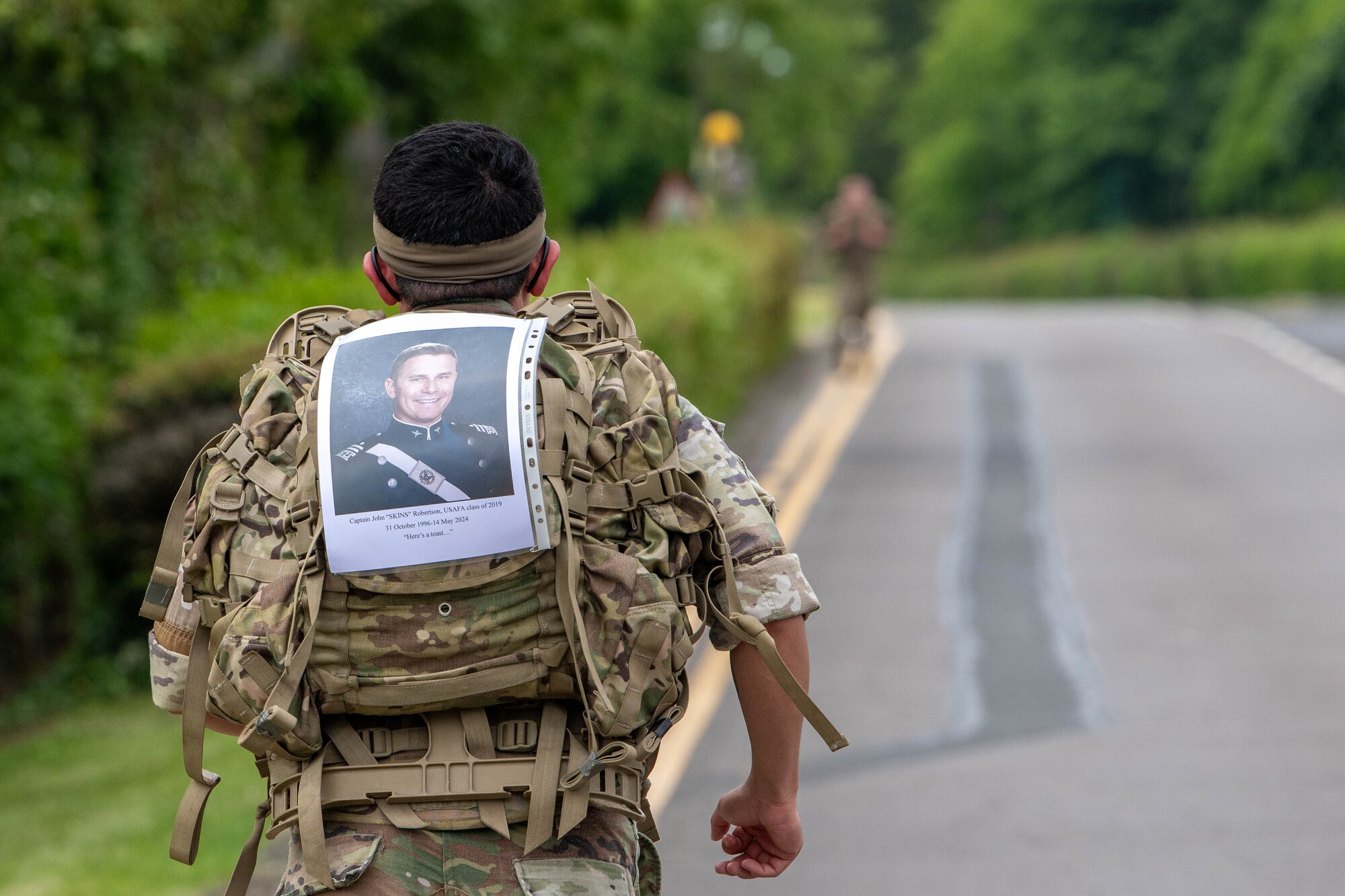 An Airman runs with a photo of a fallen member attached to his ruck sack