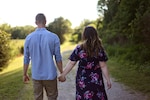 Couple holding hands walks along a path in nature