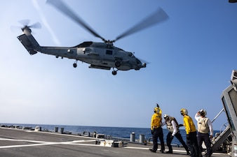 Sailors aboard USS Higgins (DDG 76) watch as a helicopter from HSM-77 takes off while underway in the Philippine Sea.
