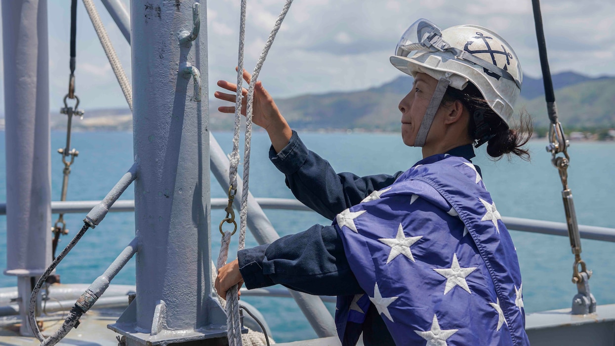 BM1 Yin Su lowers the ensign oaboard USS Harpers Ferry (LSD 49) as the ship departs Cebu, Philippines.
