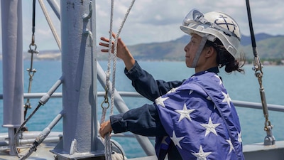 BM1 Yin Su lowers the ensign oaboard USS Harpers Ferry (LSD 49) as the ship departs Cebu, Philippines.
