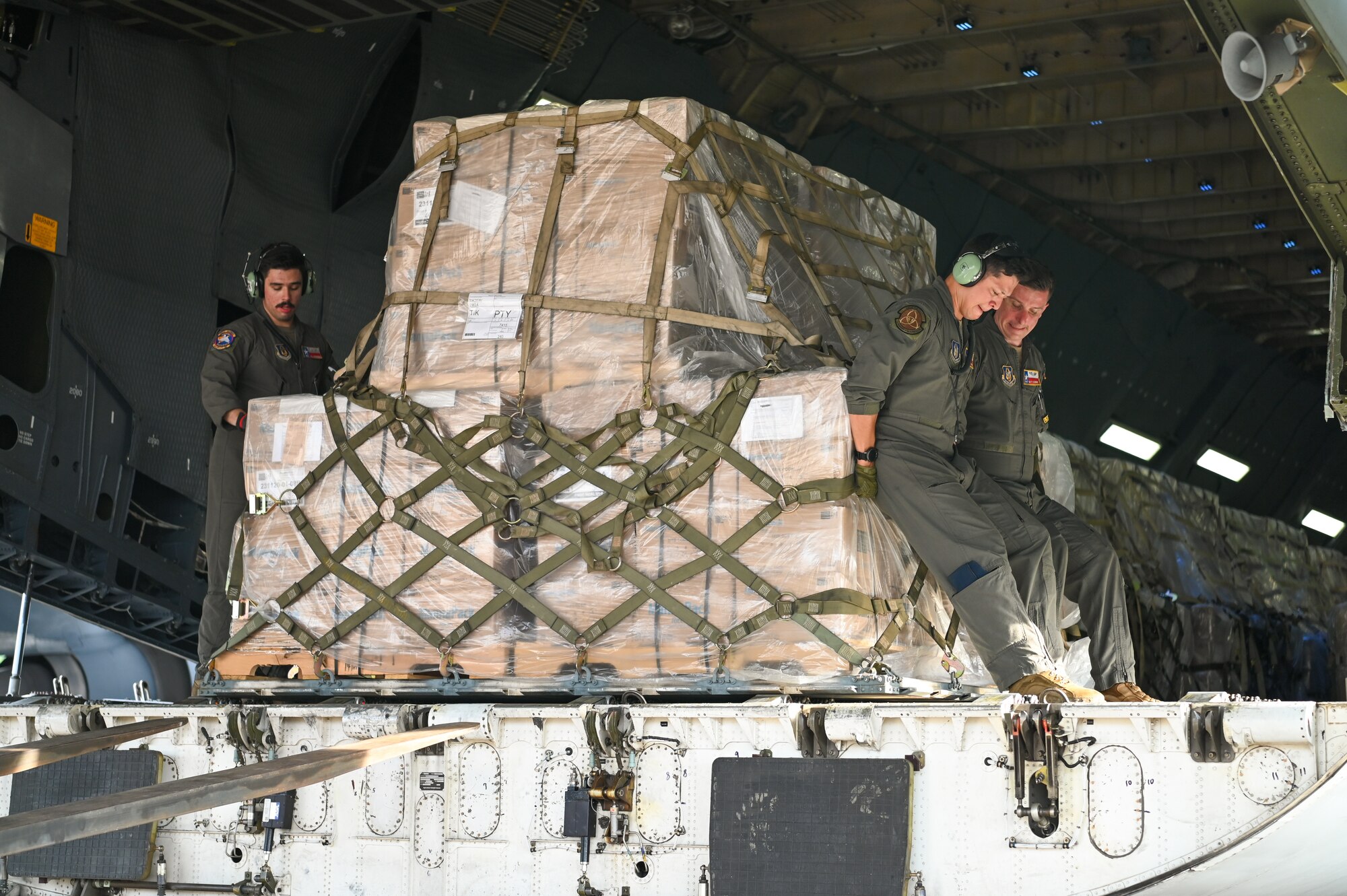 Master Sgt. Matthew Legendre, Master Sgt. Brent Bolin, and Senior Airman Ali Gundogdu, 68th Airlift Squadron loadmasters, position a pallet of humanitarian aid being offloaded from a 433rd Airlift Wing C-5M Super Galaxy at Panama Pacifico International Airport June 1, 2024.