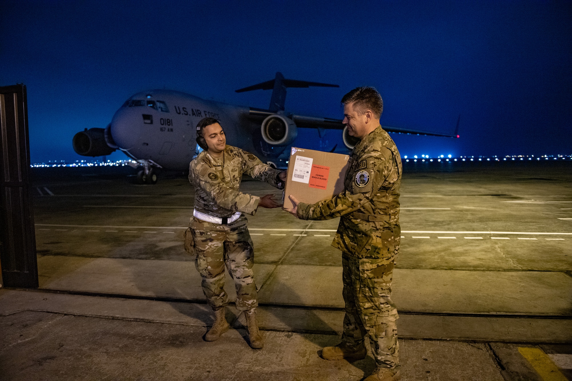 U.S. Air Force Staff Sgt. Thiago Goes, 70th Aerial Port Squadron special handler/joint inspector, gives Col. Brian Gavitt, Combined Joint Task Force - Resolute Sentinel Surgeon General and 346th Expeditionary Operational Medical Readiness Squadron commander, a box of donated blood during exercise Resolute Sentinel 2024 in Lima, Peru, May 30, 2024. The blood was requested and within 24 hours was shipped from Joint Base Charleston, South Carolina, to Lima. RS24 is a three-week exercise that will integrate combat interoperability and disaster response training, in addition to space domain awareness, medical and legal exchanges, humanitarian aid and construction projects. (U.S. Air Force photo by Senior Airman Courtney Sebastianelli)