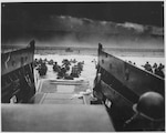 U.S. Soldiers disembark a landing craft under heavy fire off the coast of Normandy, France, June 6, 1944. (Photo Credit: National Archives U.S. Coast Guard Collection)