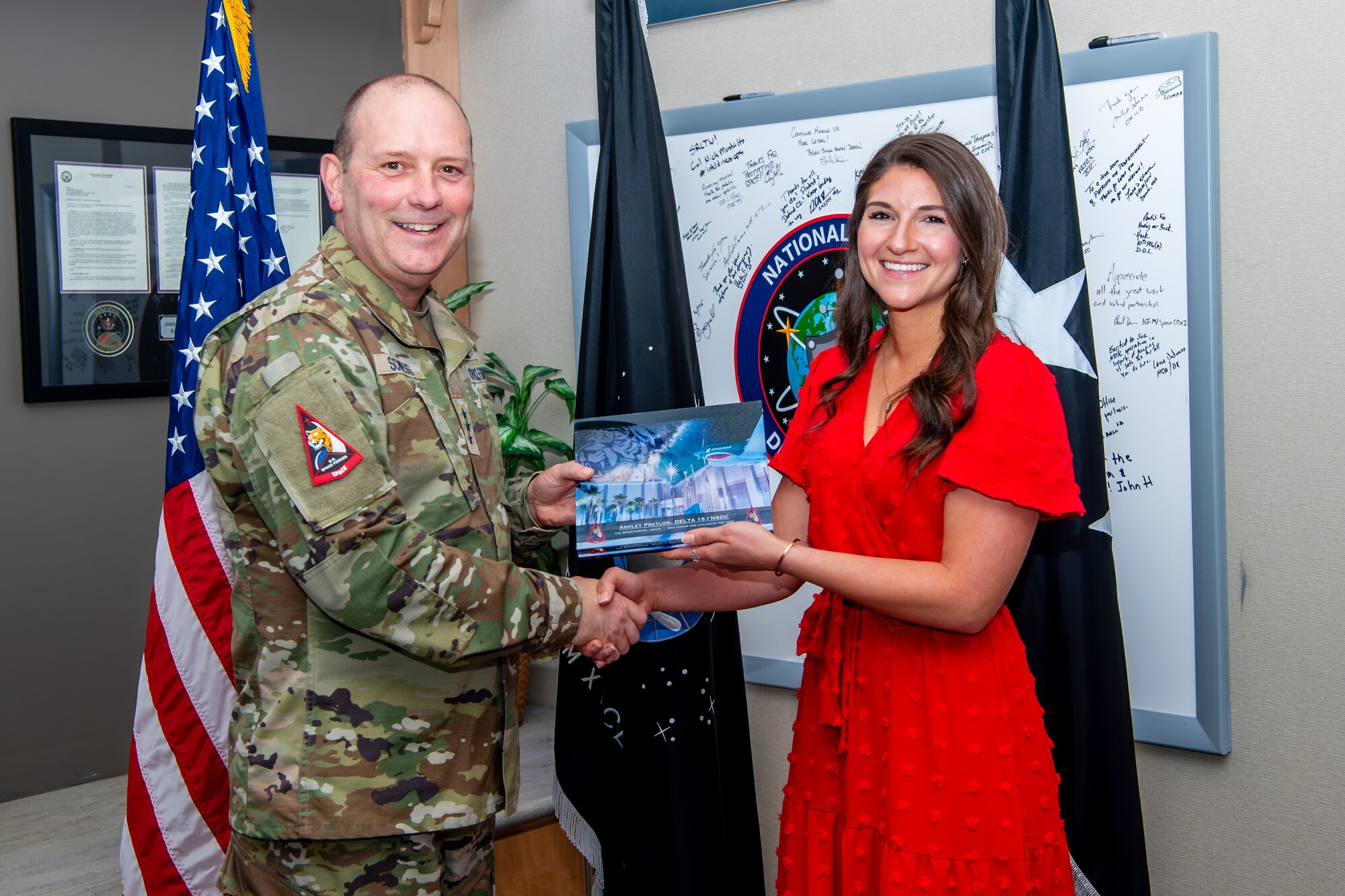 two people shaking hands holding an award plaque