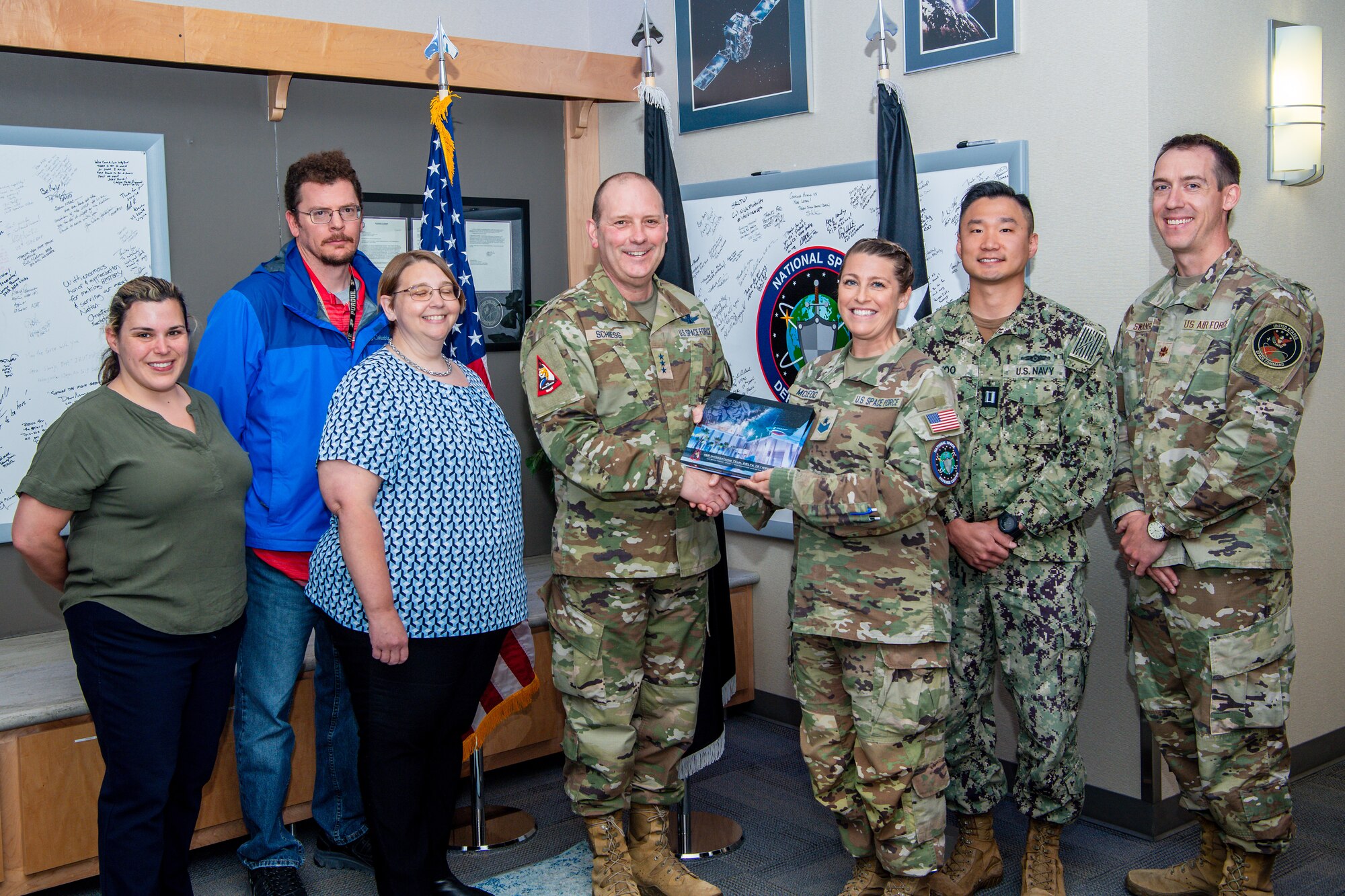 Group photo of military and civilian members posing with an award plaque