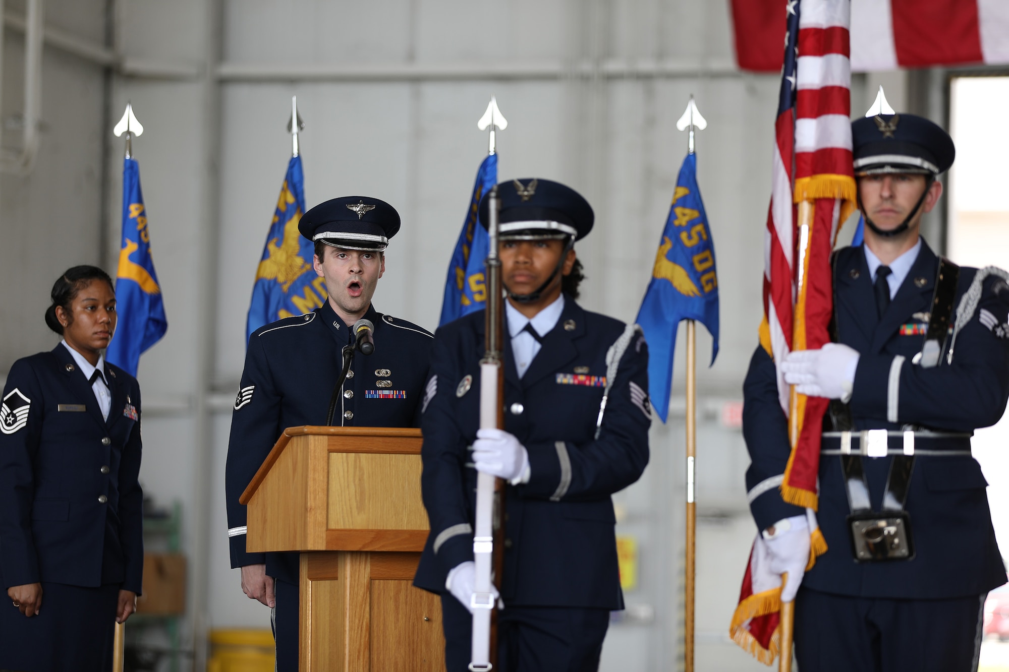A member of the Air Force Band of Flight sings the National Anthem as the 445th Airlift Wing Honor Guard stands at attention after presenting the Colors during the 445th Airlift Wing Assumption of Command ceremony held at Wright-Patterson Air Force Base, Ohio June 1, 2024.  Col. Perry assumed command of the wing after serving as the commander of the 434th Operations Group, Grissom Air Reserve Base, Indiana. (U.S. Air Force photo/Senior Airman Angela Jackson)