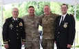 four men pose for a photo after the change of command ceremony.