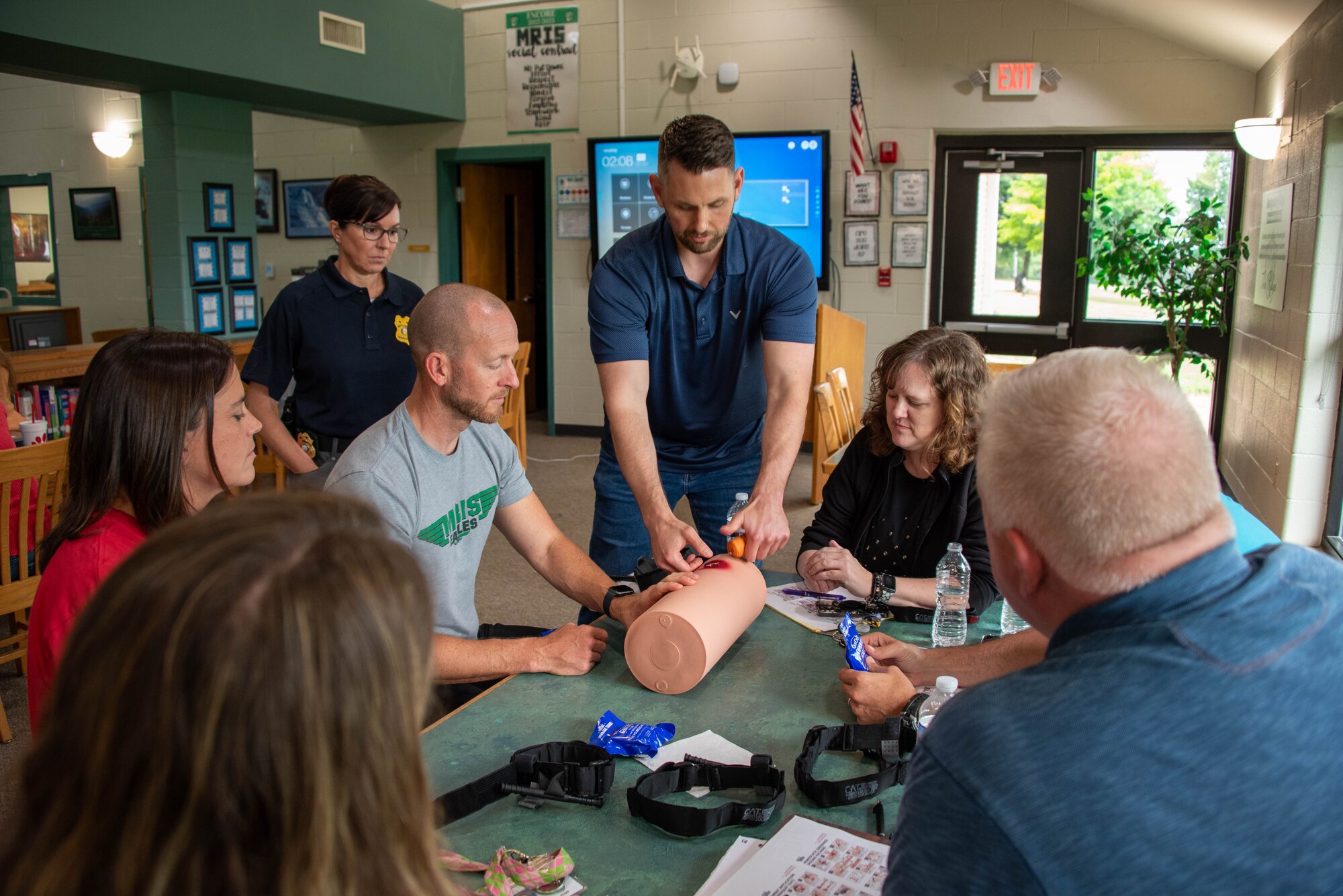 a man demonstrates packing a simulated wound while multiple people watch