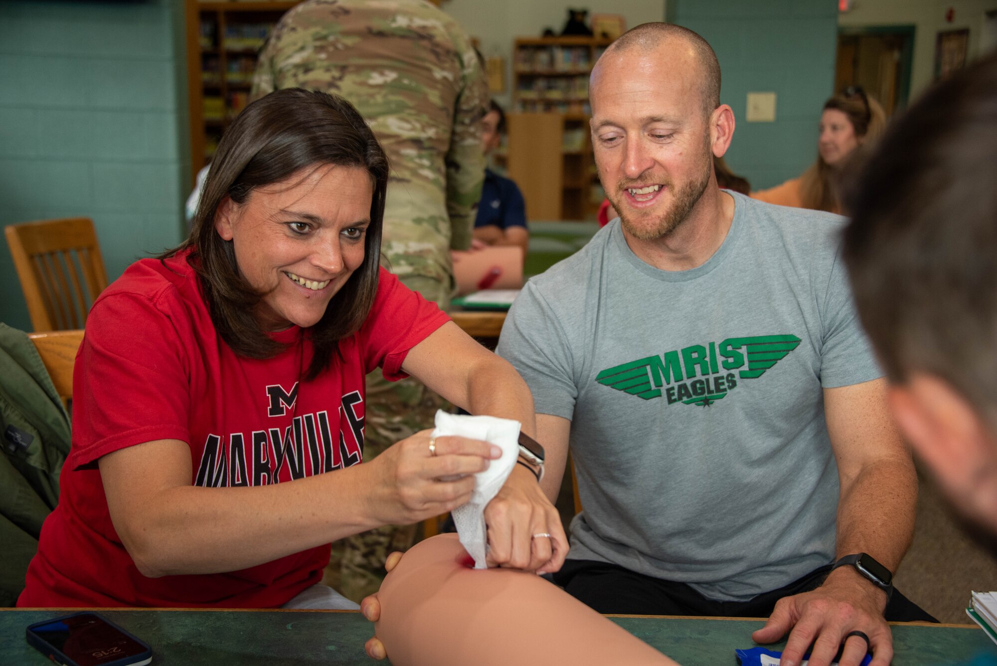 a man watches while a woman packs a simulated wound
