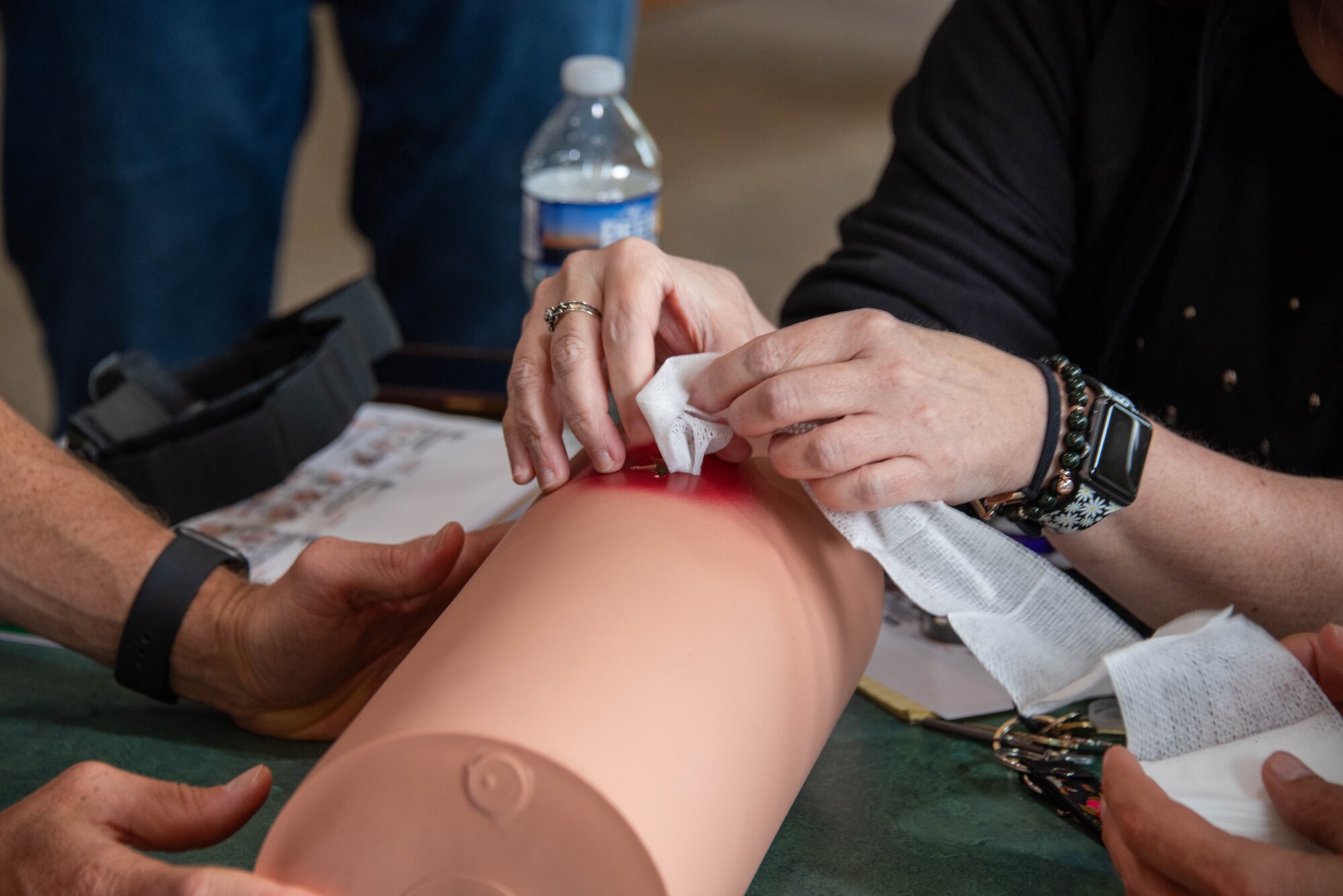 a pair of hands wadding material to pack into a simulated wound