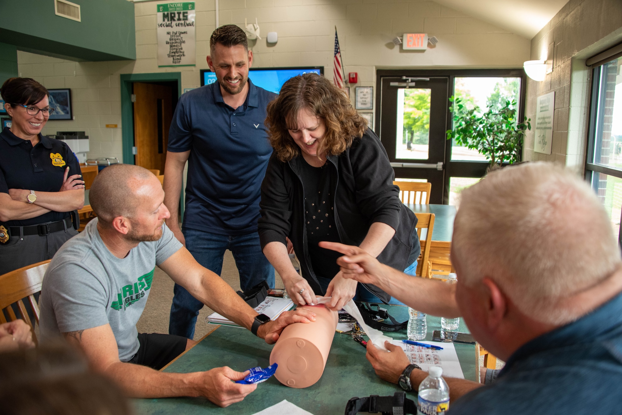 a woman practices wound packing on a dummy surrounded by other people