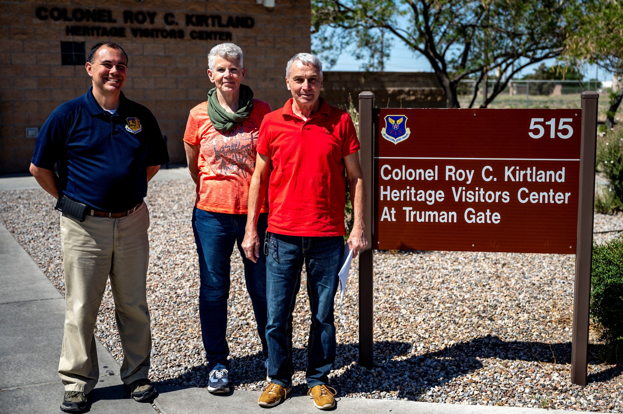 Three people pose for a photo by a sign.