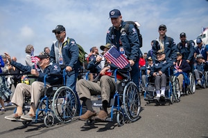 Civilians push veterans in in wheelchairs past a crowd of well-wishers on a flight line.