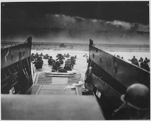 U.S. Soldiers disembark a landing craft under heavy fire off the coast of Normandy, France, June 6, 1944. (Photo Credit: National Archives U.S. Coast Guard Collection)
