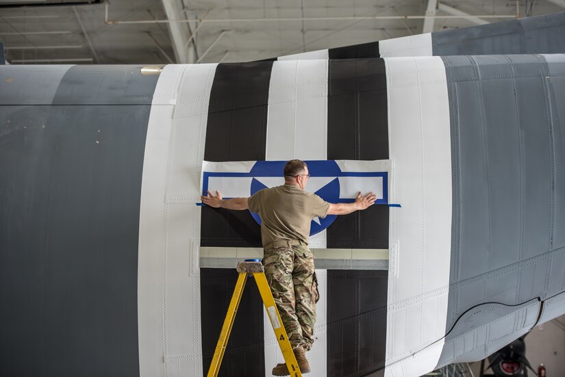 Master Sgt. Lee Stanley, aircraft structural shop chief for the 123rd Maintenance Squadron, affixes a World War II-style roundel to a C-130J Super Hercules aircraft at the Kentucky Air National Guard Base in Louisville, Ky., May 15, 2024, to prep the aircraft for participation in D-Day observations in France on June 6. The roundel replicates historical markings used on U.S. aircraft during the war. (U.S. Air National Guard photo by Airman 1st Class Annaliese Billings)