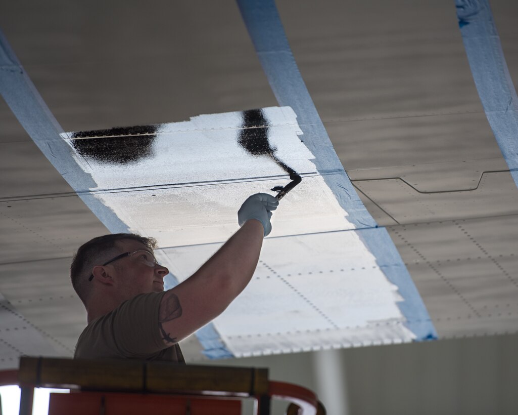 Tech. Sgt. Kyle Harris, an aircraft structural repairman from the 123rd Maintenance Squadron, paints the wing of a C-130J Super Hercules to display authentic World War II aircraft livery at the Kentucky Air National Guard Base in Louisville, Ky., May 15, 2024. The aircraft is scheduled to patriciate in D-Day observations in France on June 6 bearing the markings. (U.S. Air National Guard photo by Airman 1st Class Annaliese Billings)