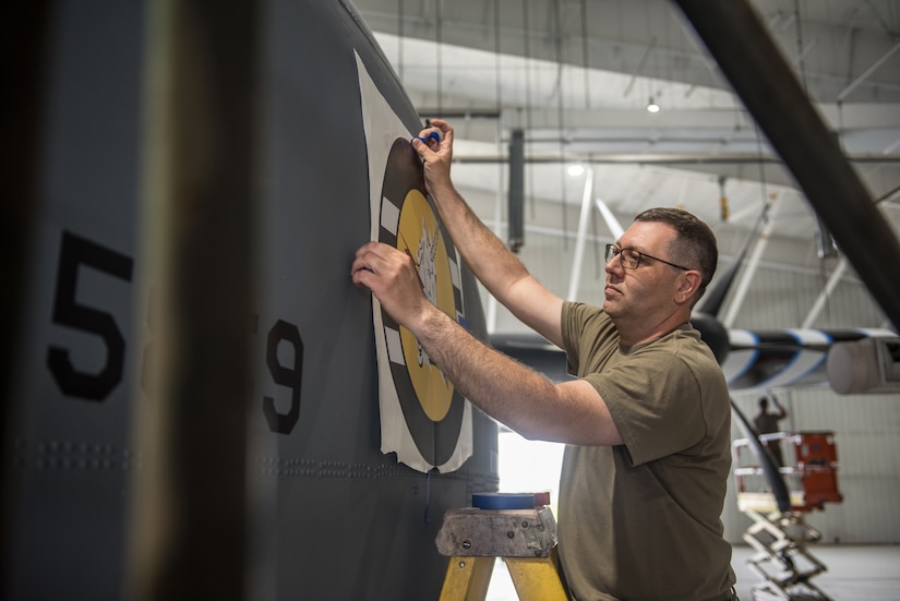 Master Sgt. Lee Stanley, aircraft structural shop chief for the 123rd Maintenance Squadron, affixes nose art to a C-130J Super Hercules at the Kentucky Air National Guard Base in Louisville, Ky., May 15, 2024, to prep the aircraft for participation in D-Day observations in France on June 6. The art features a unicorn and lightning bolt, which were prominent components of unit heraldry belonging to the 368th Fighter Squadron, from which the Kentucky Air National Guard’s lineage originates. (U.S. Air National Guard photo by Airman 1st Class Annaliese Billings)