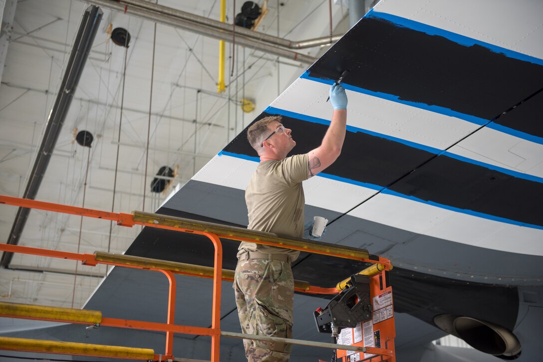 Tech. Sgt. Kyle Harris, an aircraft structural repairman from the 123rd Maintenance Squadron, paints the wing of a C-130J Super Hercules to display authentic World War II aircraft livery at the Kentucky Air National Guard Base in Louisville, Ky., May 15, 2024. The aircraft is scheduled to patriciate in D-Day observations in France on June 6 bearing the markings. (U.S. Air National Guard photo by Airman 1st Class Annaliese Billings)
