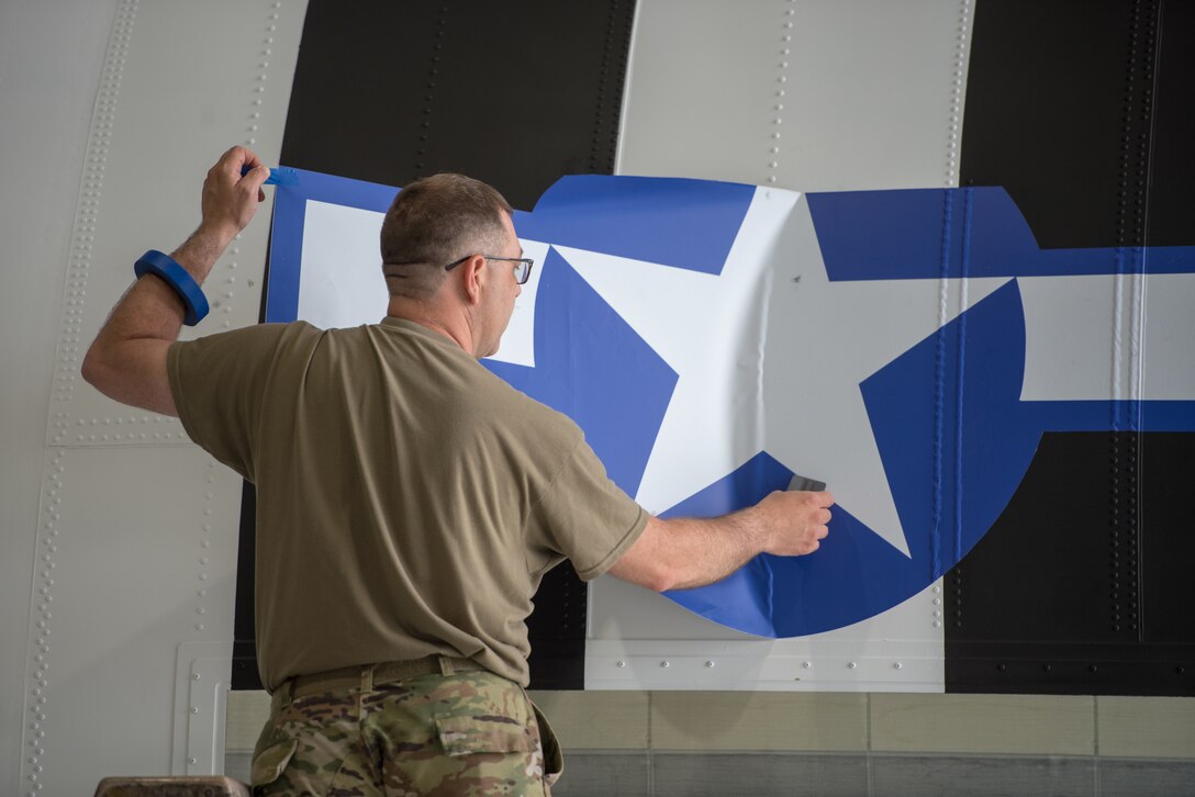 Master Sgt. Lee Stanley, aircraft structural shop chief for the 123rd Maintenance Squadron, affixes a World War II-style roundel to a C-130J Super Hercules aircraft at the Kentucky Air National Guard Base in Louisville, Ky., May 15, 2024, to prep the aircraft for participation in D-Day observations in France on June 6. The design was used on U.S. aircraft during the D-Day Invasion in 1944. (U.S. Air National Guard photo by Airman 1st Class Annaliese Billings)