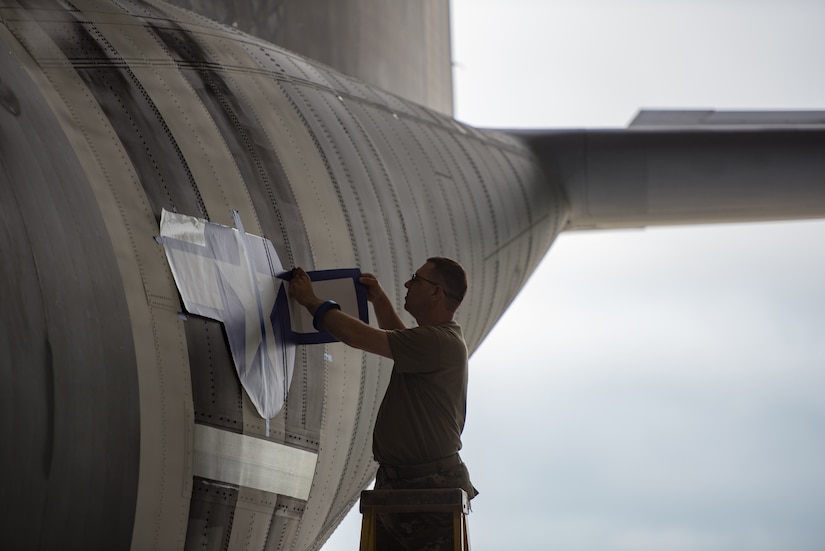 Master Sgt. Lee Stanley, aircraft structural shop chief for the 123rd Maintenance Squadron, affixes a World War II-style roundel to a C-130J Super Hercules aircraft at the Kentucky Air National Guard Base in Louisville, Ky., May 15, 2024, to prep the aircraft for participation in D-Day observations in France on June 6. The design was used on U.S. aircraft during the D-Day Invasion in 1944. (U.S. Air National Guard photo by Airman 1st Class Annaliese Billings)