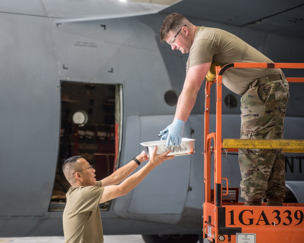 Tech. Sgt. Chang Shin, left, and Tech. Sgt. Kyle Harris, aircraft structural repairmen from the 123rd Maintenance Squadron, paint the wing of a C-130J Super Hercules to display authentic World War II aircraft livery at the Kentucky Air National Guard Base in Louisville, Ky., May 15, 2024. The aircraft is scheduled to patriciate in D-Day observations in France on June 6 bearing the markings. (U.S. Air National Guard photo by Airman 1st Class Annaliese Billings)