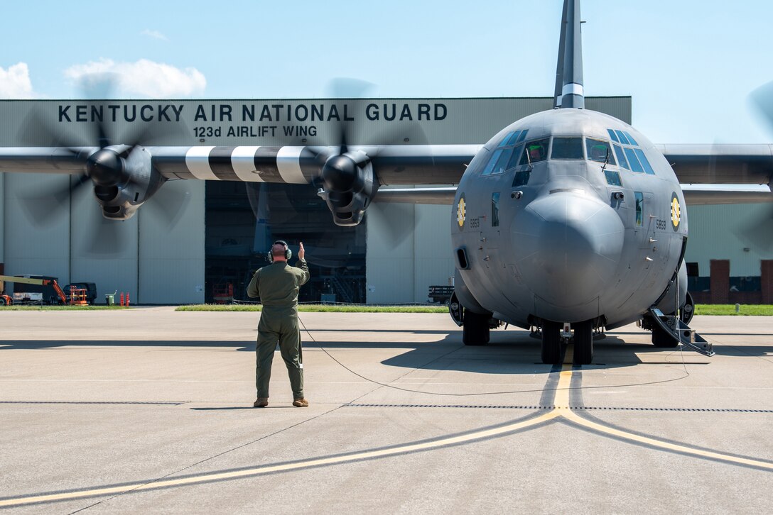 A loadmaster from the 165th Airlift Squadron signals the pilot of a C-130J Super Hercules prior to the aircraft’s departure from the Kentucky Air National Guard base in Louisville, Ky., on May 21, 2024. The plane, which bears distinctive livery replicating the markings of U.S. aircraft in World War II, will fly over France on June 6 in observance of the 80th anniversary of D-Day. (U.S. Air National Guard photo by Phil Speck)