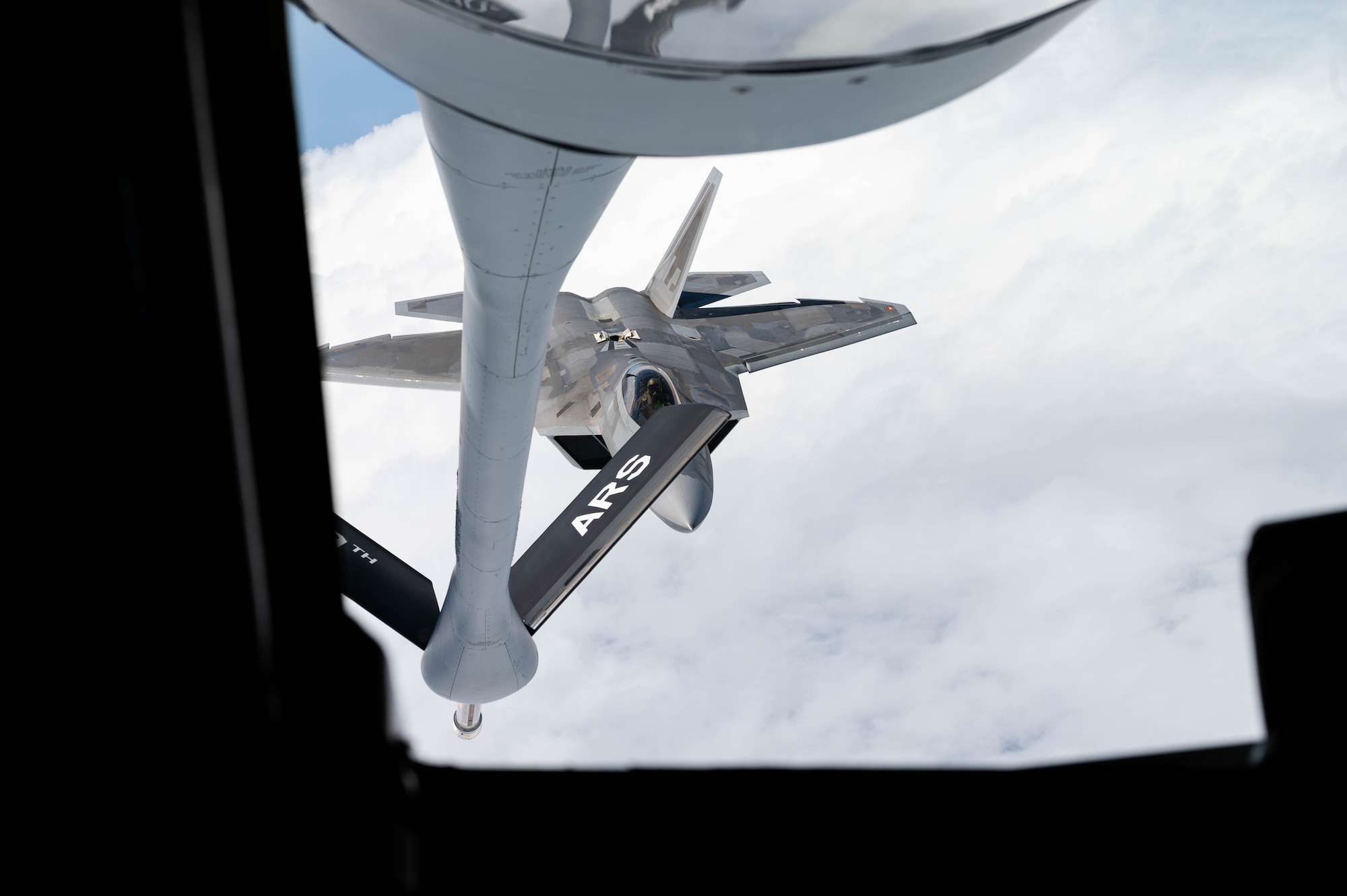 A U.S. Air Force F-22A Raptor operated by the 199th and 19th Fighter Squadrons approaches a KC-135 Stratotanker to conduct aerial refueling.