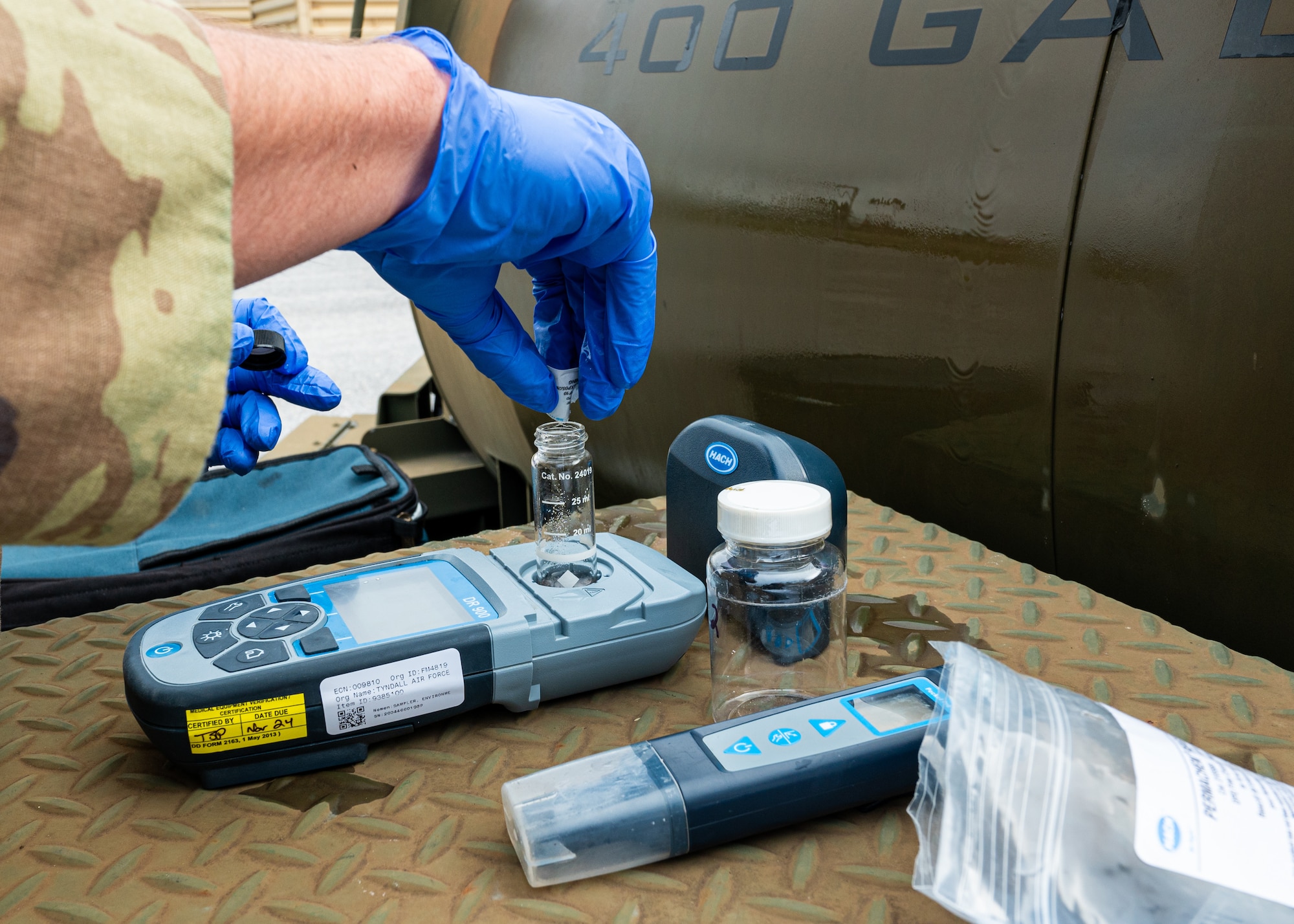 a bioenvironmental engineering technician pours chlorine reagent into a water sample bottle