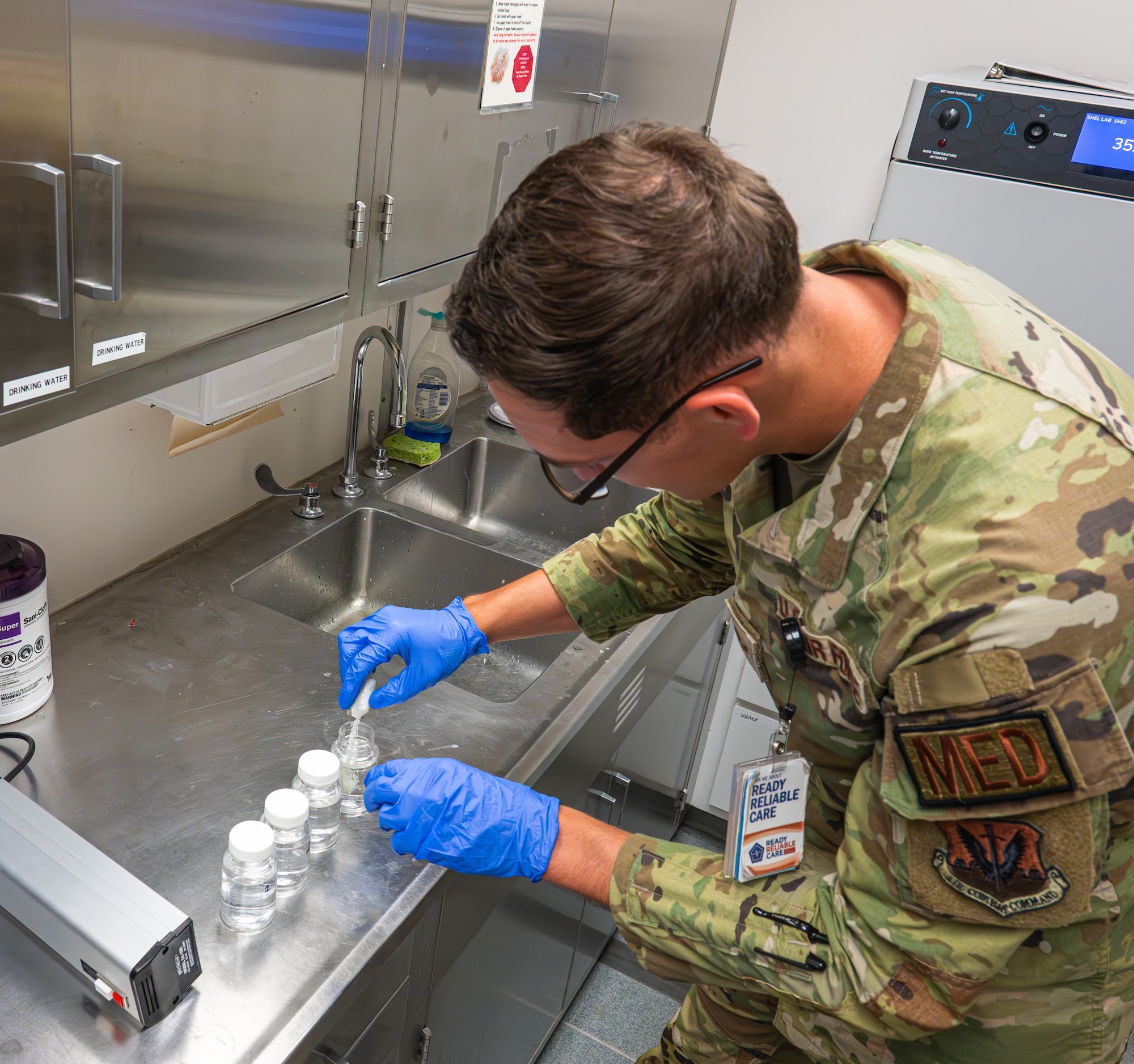 A bioenvironmental engineering technician pours Colilert powder into water samples