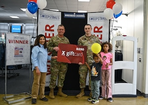 A Space Launch Delta 30 vice commander (left), a Vandenberg Space Force Base Exchange general manager (left), a guardian from the 18th Space Defense Squadron and his children (right) pose for a photo at VSFB.