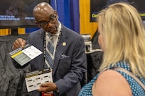 Dr. Timothy Lucas, U.S. Army Corps of Engineers financial management certification program manager, shows off briefing cards about the courses offered through the U.S. Army Finance and Comptroller School and the U.S. Army Financial Management Command’s military spouse job transfer program to Jennifer Dubbs, USAFMCOM financial management systems analyst, at the U.S. Army finance and comptroller booth during the Society of Defense Financial Management’s Profession Development Institute in Phoenix May 29, 2024. The PDI was a chance for the Army’s finance and comptroller organizations to come together, share best practices, solve shared problems, and professionally develop Soldiers and Army civilian employees. (U.S. Army photo by Mark R. W. Orders-Woempner)