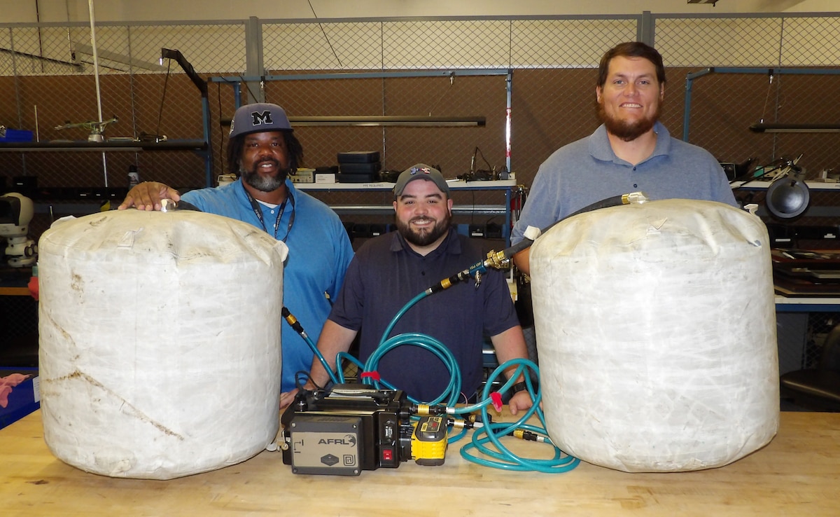 From left: Wright Brothers Institute Computer and Electronics Engineer Claud Nichol, University of Dayton Research Institute Mechanical Engineer Jason Adams and Air Force Research Laboratory Center for Rapid Innovation Mechanical Engineer John “J.D.” Bales, stand with a heavy lift kit, or HLK, which they modified to allow the bags to be deflated more quickly in dangerous environments at the Wright Brothers Institute Proving Ground Facility on May 21, 2024. The Heavy Lift Kit can be used by first responders to lift objects weighing as much as 45,000 pounds using two inflatable bags. (U.S. Air Force photo / Patrick Foose).