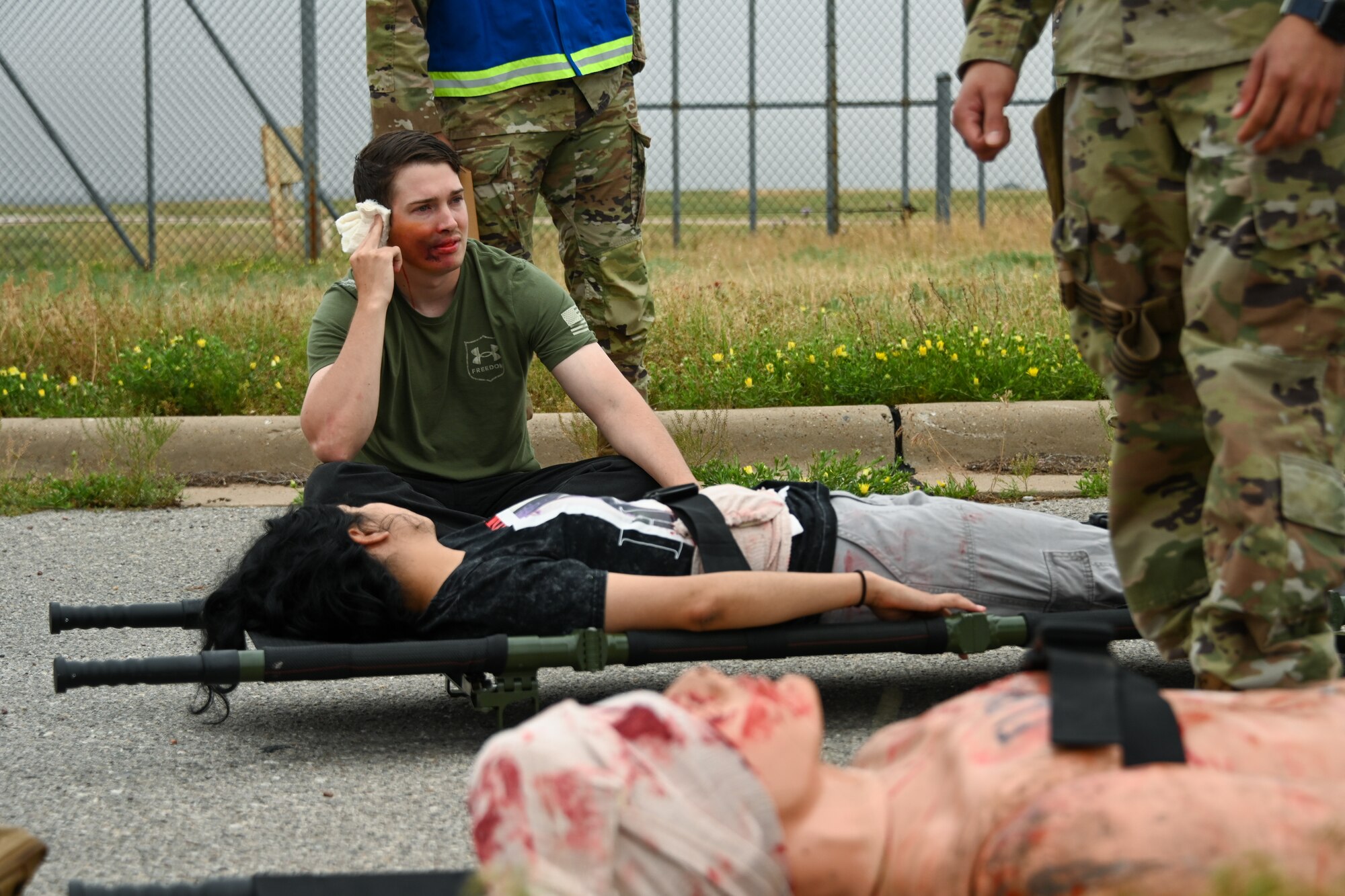 U.S. Air Force Tech. Sgt. Austin Stevenson, 97th Operational Medical Readiness Squadron public health technician, and Airman Sujey Arteza Cardoza, 71st Healthcare Operations Squadron medical administrator, imitate injured patients at Altus Air Force Base, Oklahoma, May 23, 2024. The service members were tasked to take care of the injured Airmen as part of the Caduceus Spear exercise. (U.S. Air Force photo by Airman Lauren Torres)