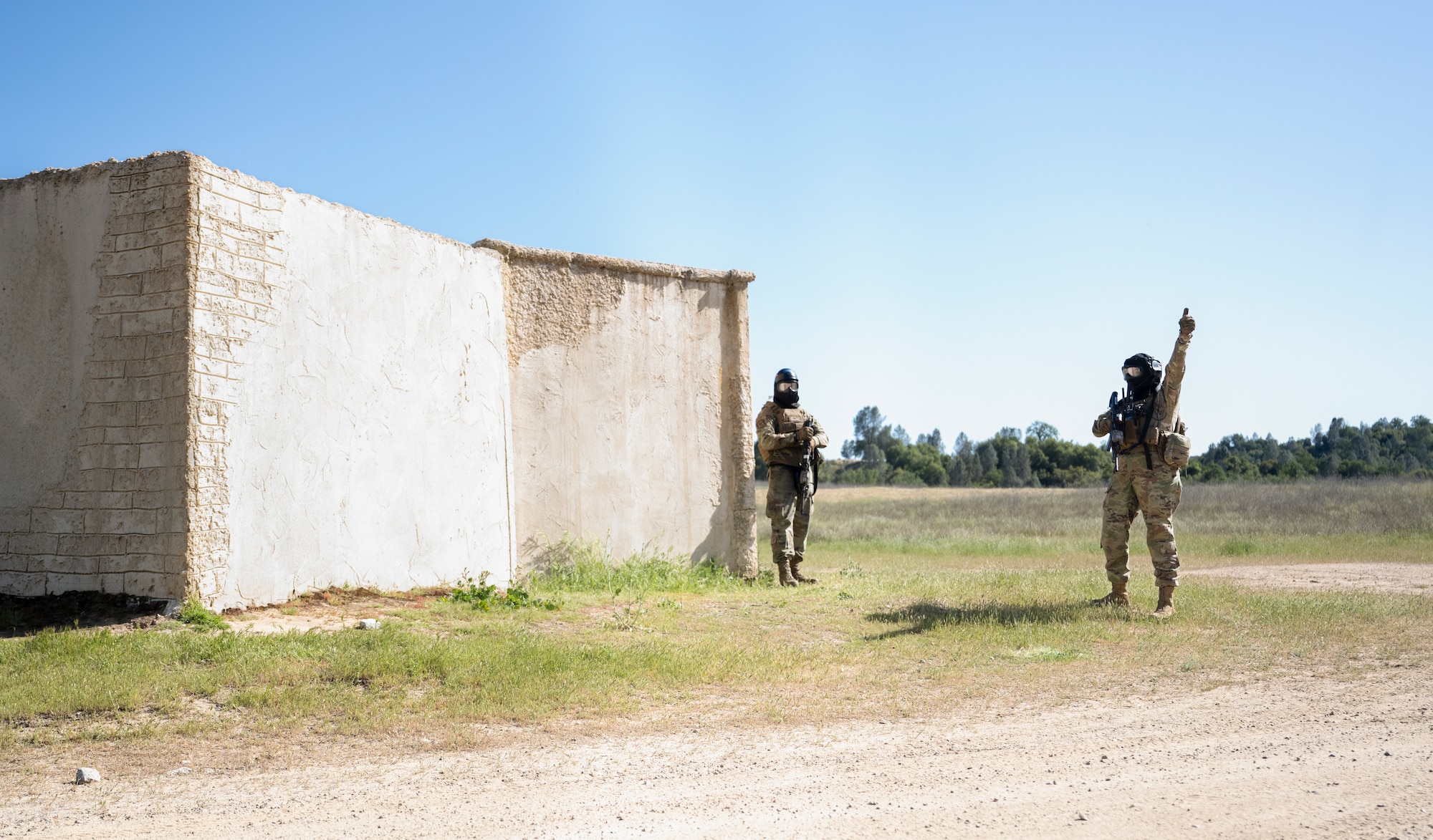 U.S. Air Force Staff Sgt. Mackenzie Wenham, right, an 821st Contingency Response Squadron aerial port supervisor, signals that her team is ready to conduct a building clearing drill during Exercise HADES SENTINEL at Fort Hunter-Liggett in Jolon, California, May 1, 2023.