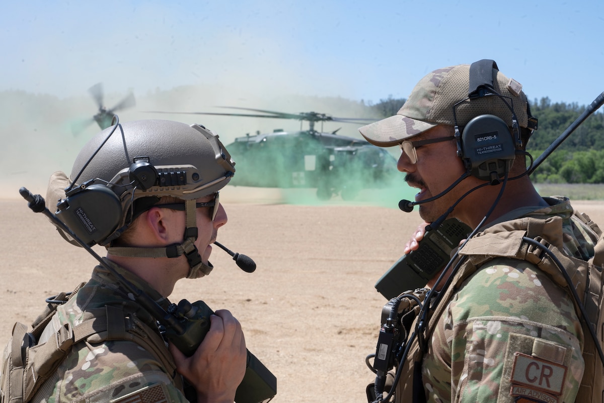 U.S. Air Force Capt. Trevor Wolfe, left, an 821st Contingency Response Group executive, and Tech. Sgt. Steven Ramos, right, an 821st Contingency Response Squadron airfield manager, assist a UH-60L Black Hawk helicopter landing during Exercise HADES SENTINEL at Fort Hunter-Liggett in Jolon, California, May 9, 2023.