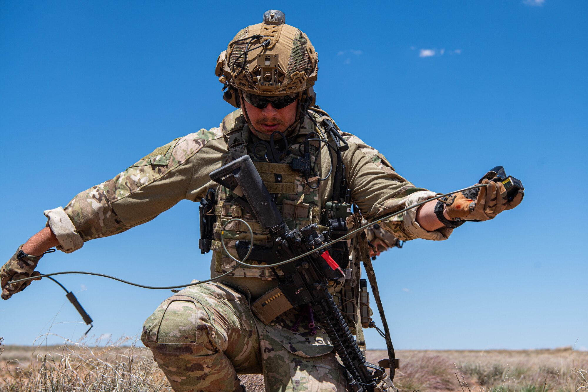 A man in military uniform manipulates military demolition equipment.