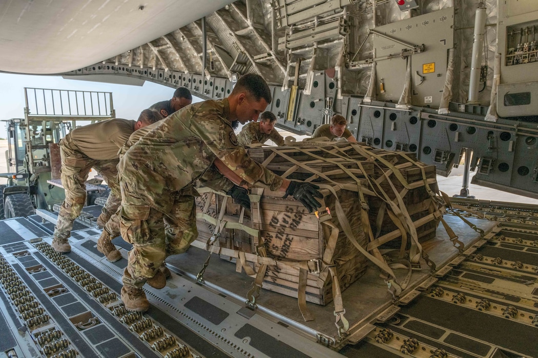 Airmen roll a cargo pallet onto a C-17 Globemaster III aircraft