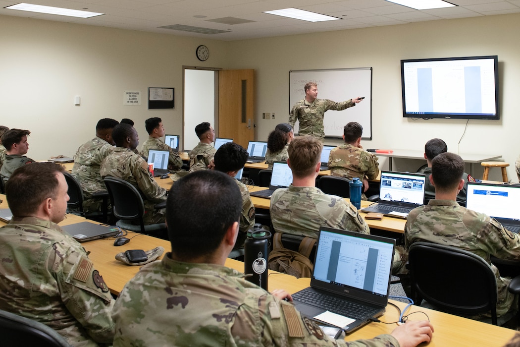 airmen sitting inside a classroom and listening to an instructor