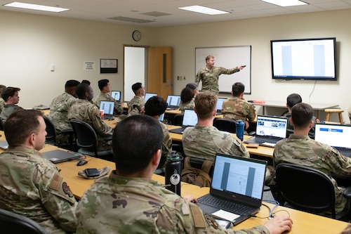 airmen sitting inside a classroom and listening to an instructor