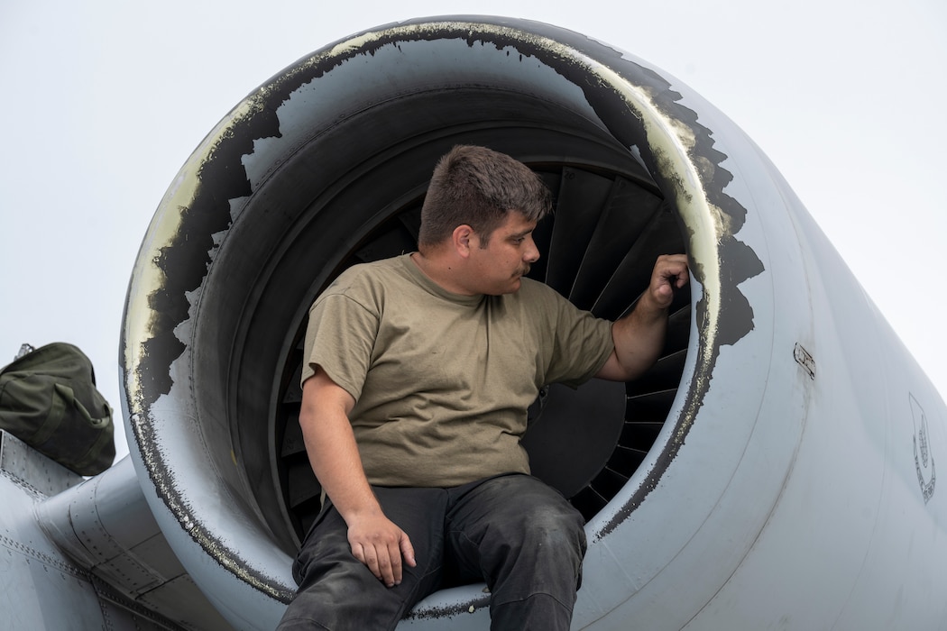 A maintainer sits inside an A-10 turbine as he inspects it.