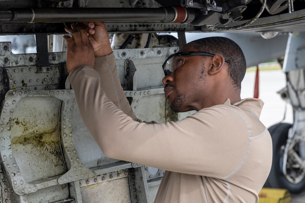 A maintainer conducts maintenance underneath an A-10 aircraft.