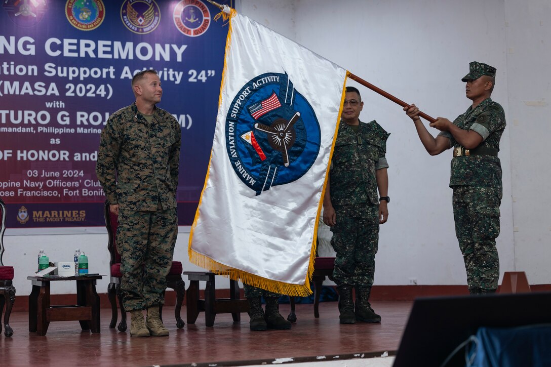 Leading representatives from the U.S. Marines Corps, Philippine Navy and Philippine Marine Corps unfurl the Marine Aviation Support Activity flag during the MASA 24 opening ceremony at Fort Bonifacio, Manila, Philippines, June 3, 2024. MASA 24 is an annual Philippine-U.S. military exercise focused on mutual defense, strengthening relationships, and rehearsing emerging aviation concepts. (U.S. Marine Corps photo by Sgt. Shaina Jupiter)