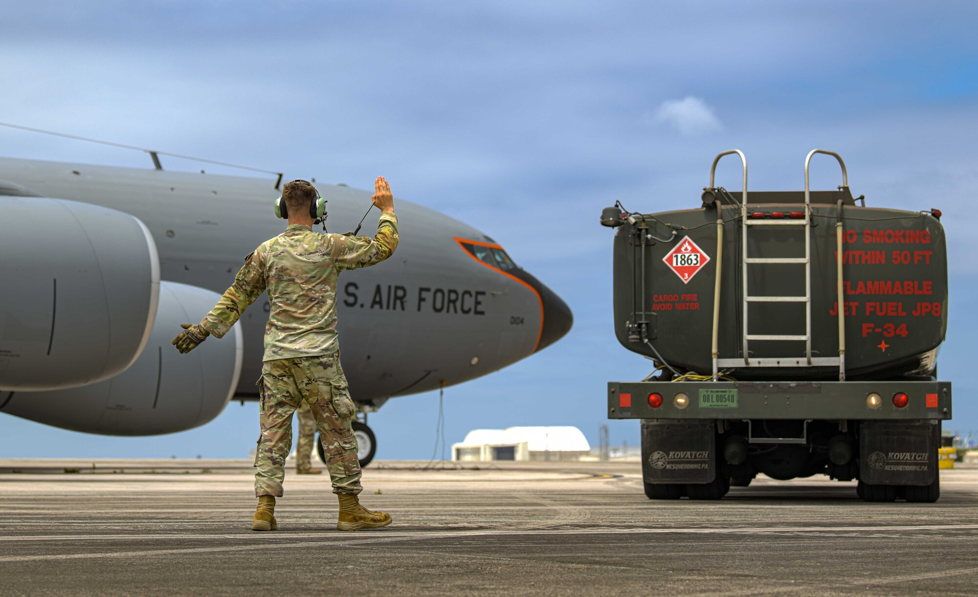 U.S. Air Force Senior Airman Michael Keller, 909th Aircraft Maintenance Unit flying crew chief, marshalls a fuel tanker into place during hot-pit refuel in support of Exercise Shogun Shootout.