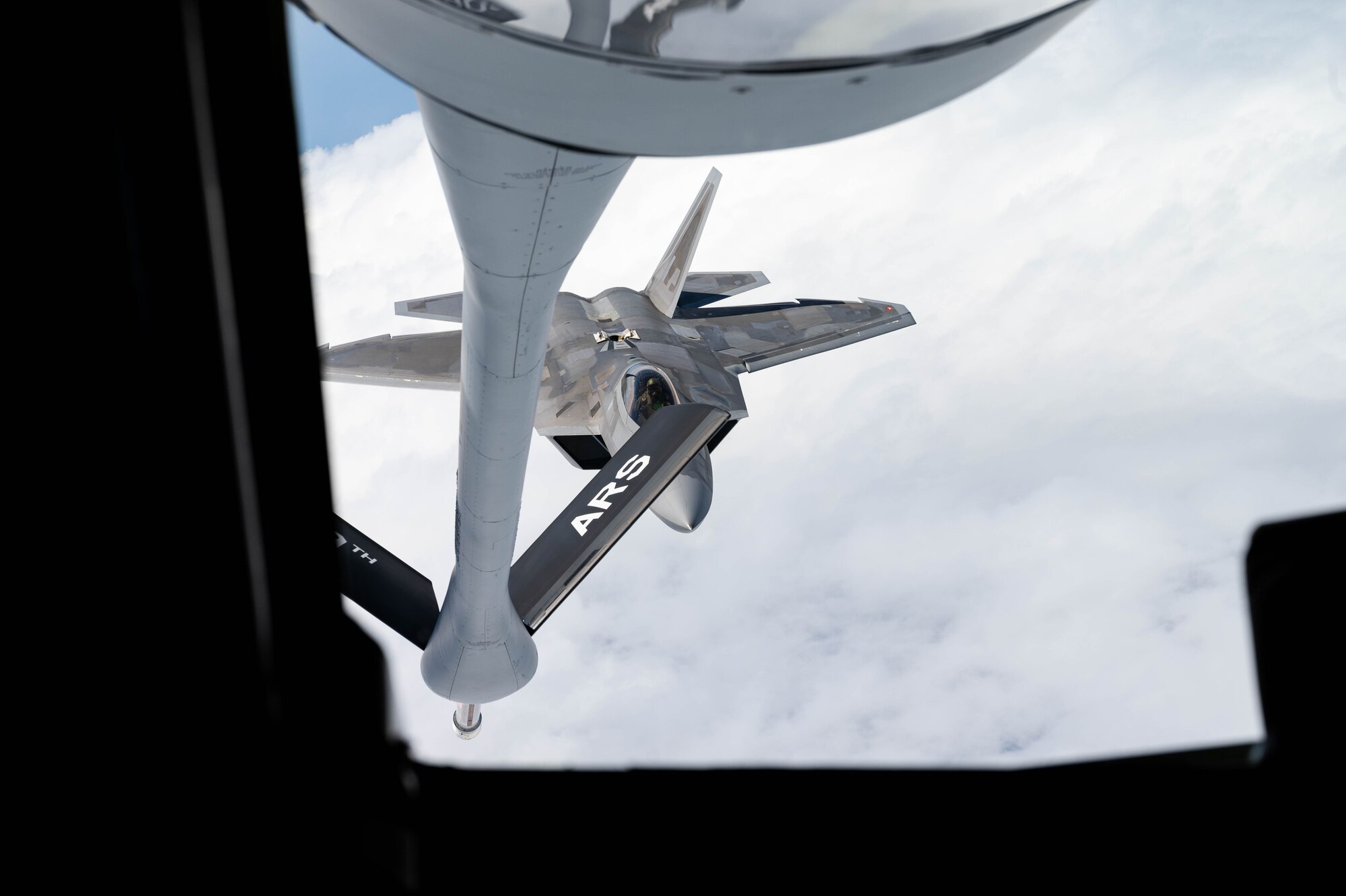 A U.S. Air Force F-22A Raptor operated by the 199th and 19th Fighter Squadrons approaches a KC-135 Stratotanker to conduct aerial refueling.