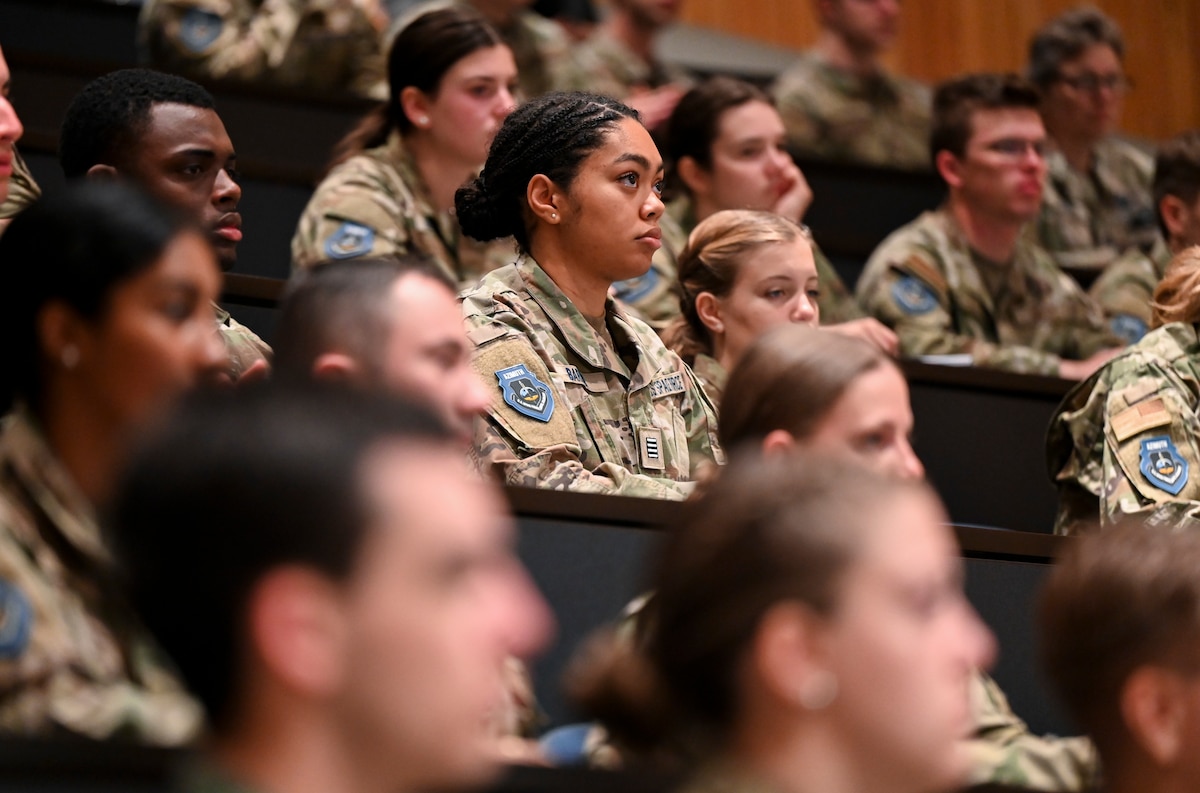 Cadets sit in an auditorium and listen to a speaker.