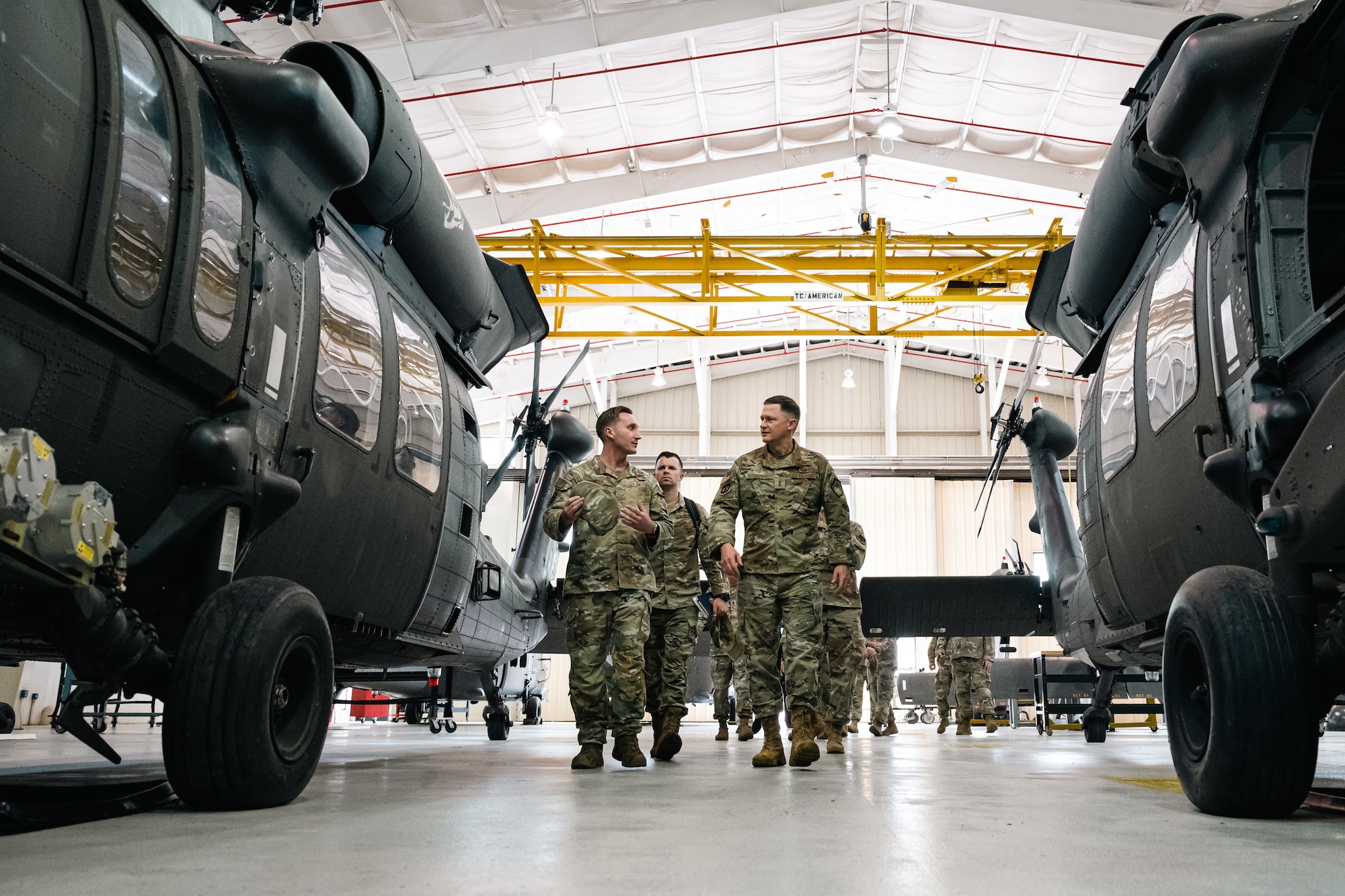 An Airman walks by two helicopters with soldiers