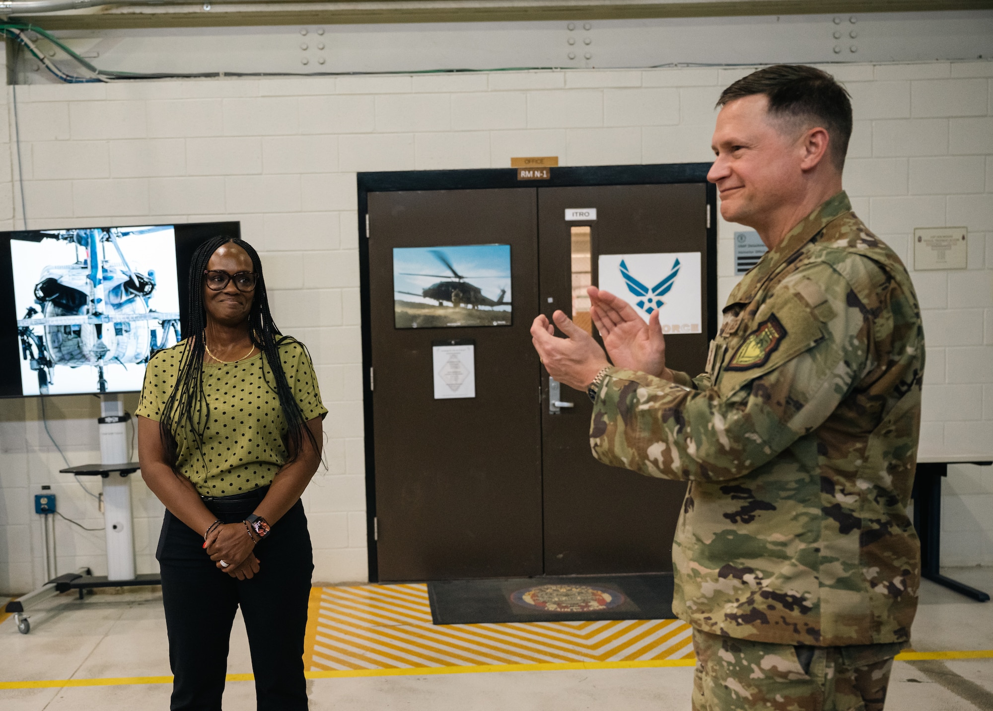 An Airman claps while a civilian on the left smiles
