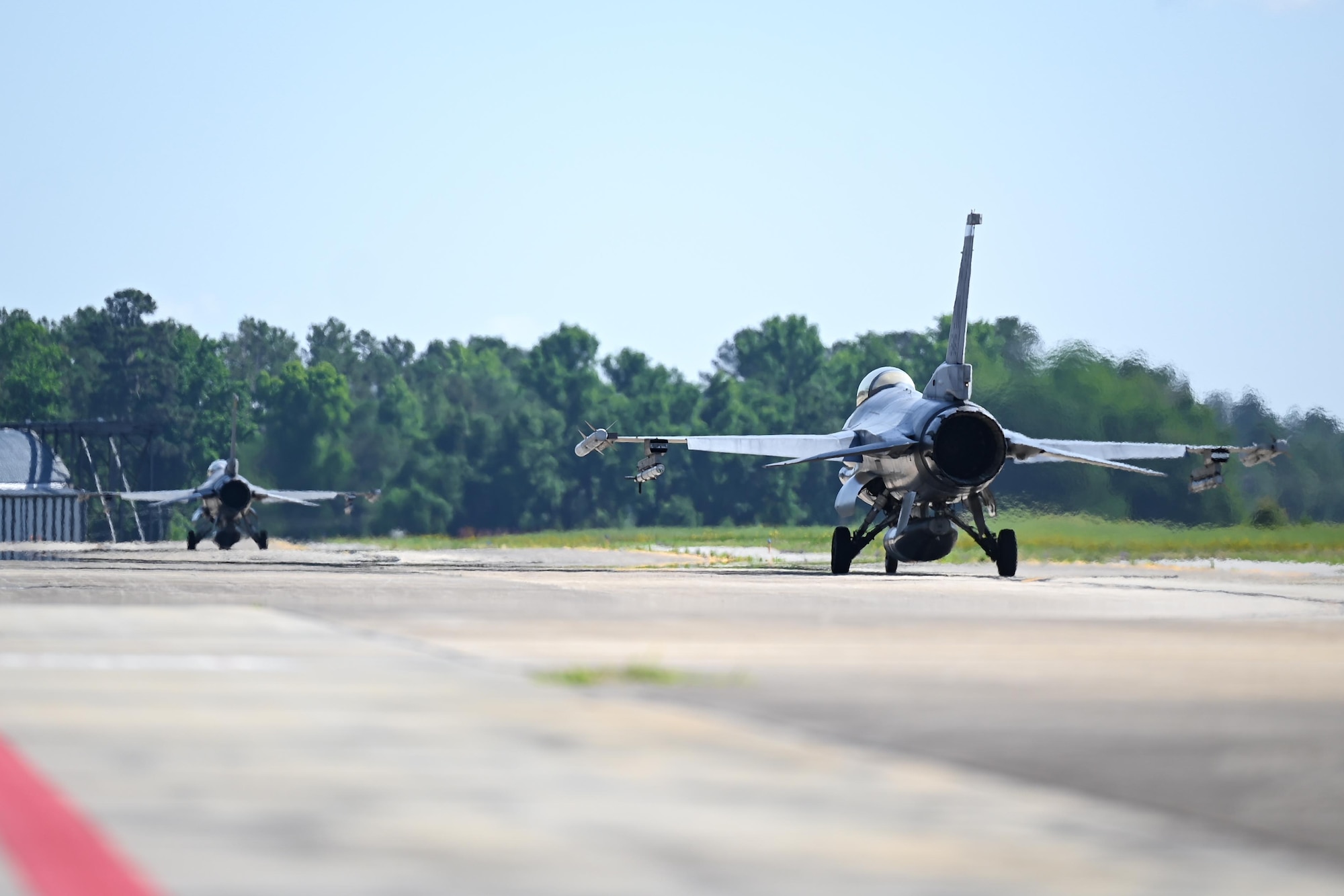 Two F-16s taxi on the flightline.