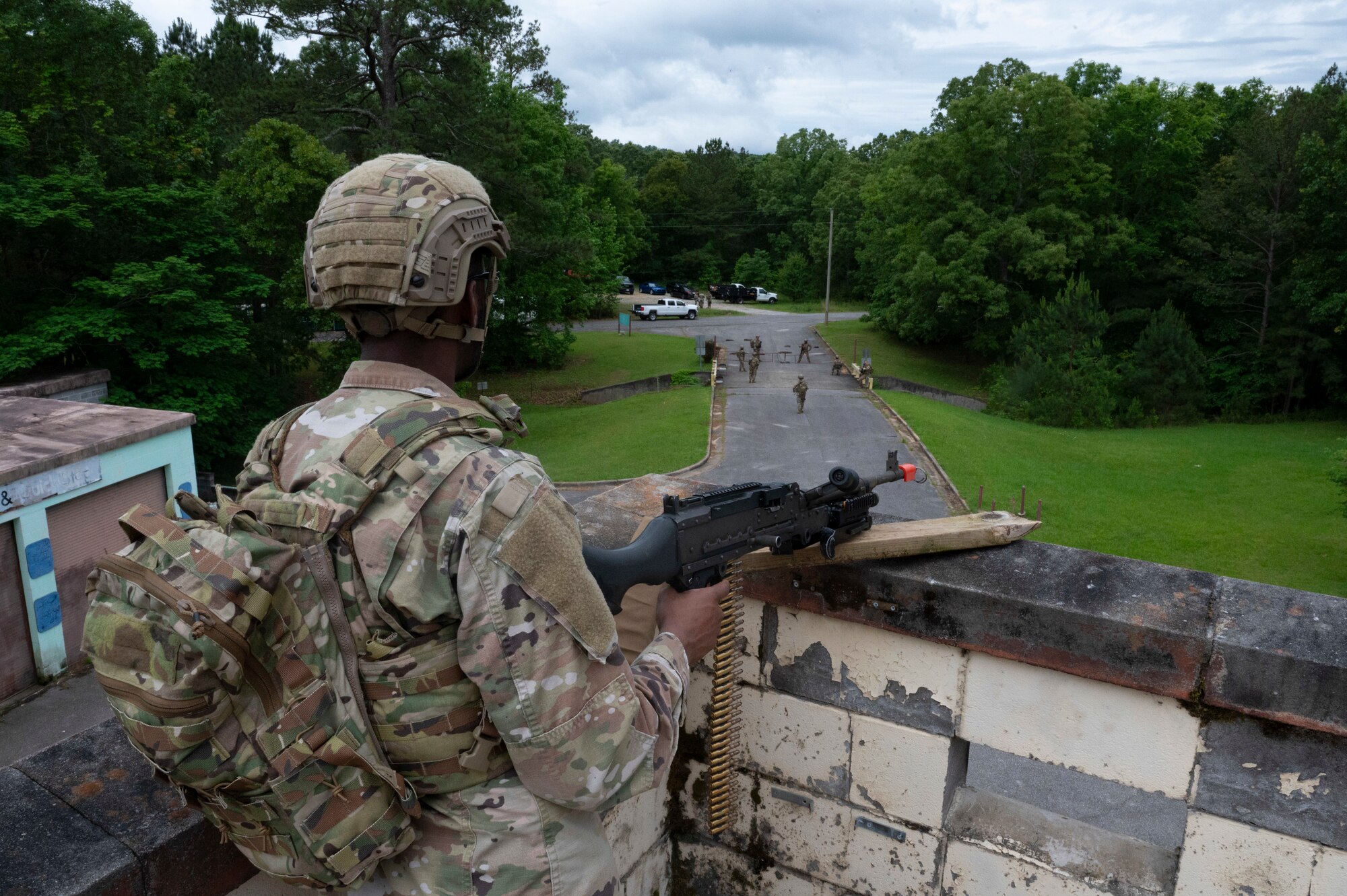 An Airman mounts his gun on a roof, looking out.